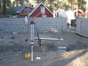 Construction site with surveying equipment and retaining wall.