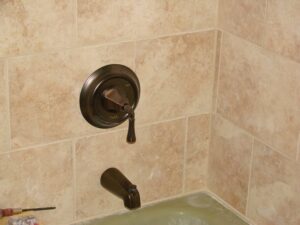 Modern shower faucet on beige tiled wall.