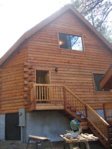 Wooden cabin exterior with stairs and construction tools.
