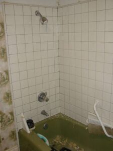 Old bathroom corner with dirty tiled shower area.