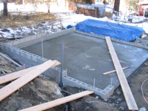 Unfinished concrete foundation construction site with materials.
