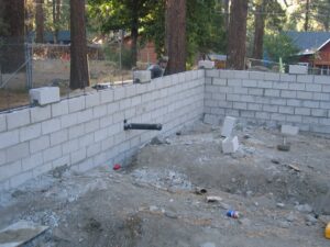 Concrete block wall construction site with worker.
