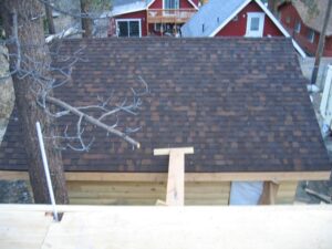 Brown shingled roof with fallen tree branches