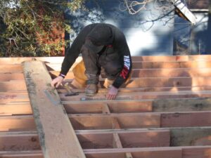 Worker installing wooden roof trusses.