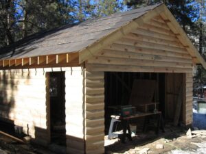 Wooden shed under construction in forest setting.