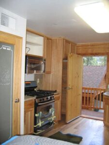 Wooden cabin kitchen interior with open door to balcony.