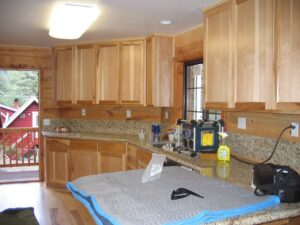 Wooden kitchen cabinets with granite countertop and cleaning supplies.