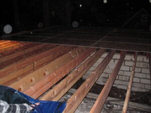 Wooden deck construction at night with snowflakes.