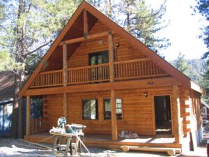 Wooden cabin with balcony in forest setting.