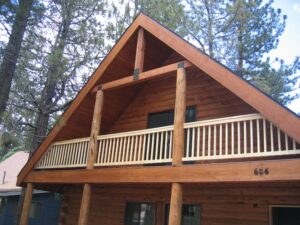 Wooden cabin exterior with balcony among pine trees.