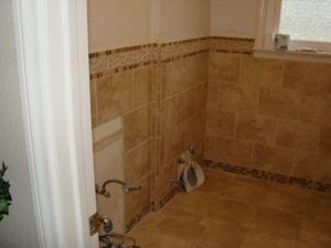 Tiled bathroom corner with shower fixtures.