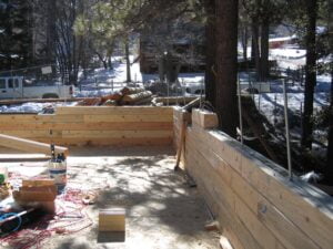 Wooden foundation framing at snowy construction site.