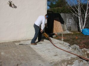 Man using jackhammer on concrete outdoor.