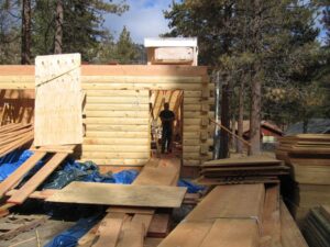 Construction site with worker building log cabin.