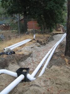 Underground pipe installation in progress on a dirt path.