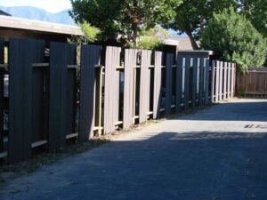 Wooden slat fence along a paved alleyway.