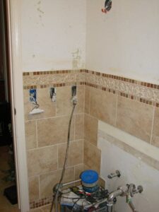 Bathroom under renovation with exposed piping and tiles.