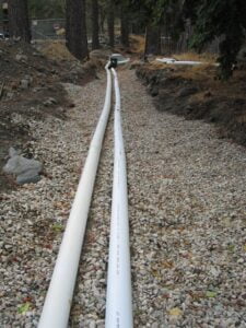 PVC pipes laid in gravel for underground utilities construction.