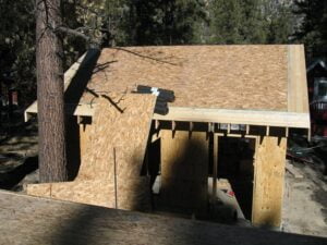 Partial wooden shed construction in forest.