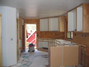 Kitchen remodeling underway with cabinets and open doorway.