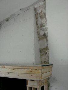 Partially installed drywall with exposed damp wall corner.
