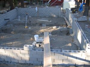 Construction site with partly built cinder block wall.