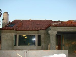 House under construction with unfinished stucco and tile roof.