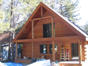 Wooden cabin under construction in forest setting.