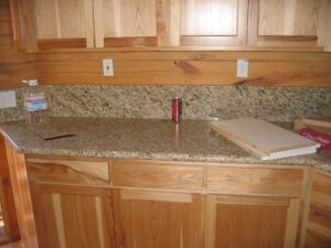 Granite countertop with wood cabinets, soda can, water bottle.