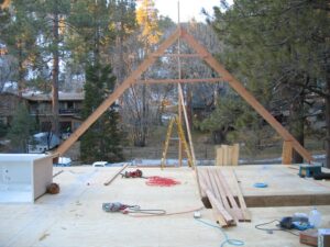 A-frame house construction in forest setting.