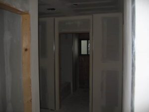 Interior under construction, unfinished drywall and doorway.