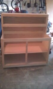 Unfinished wooden bookshelf in a garage setting.