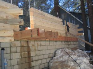 Cinder block foundation with stacked wooden beams construction.