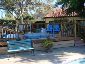 Wooden deck patio with chairs near a pool.