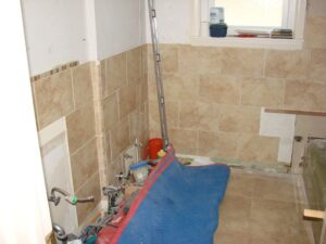 Bathroom under renovation, tile walls, exposed plumbing.